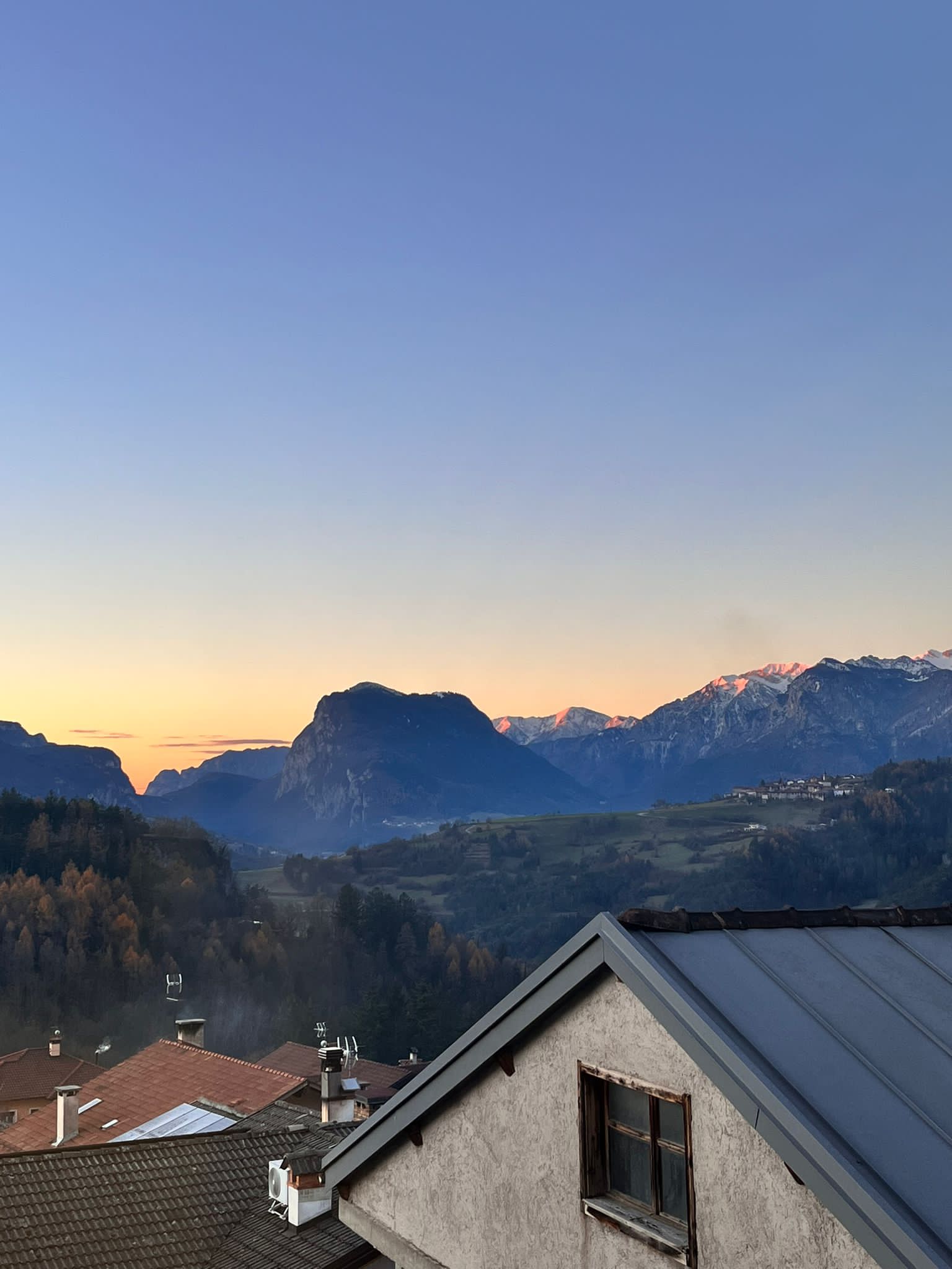 Some rooftops in the foreground. In the background, the sunrise over the mountains.